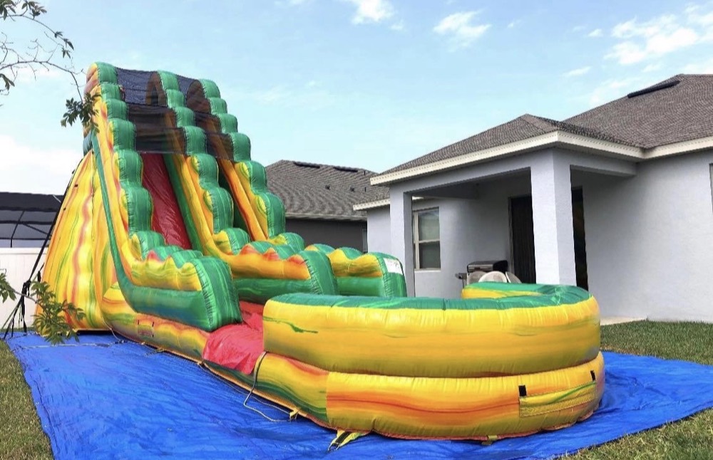 22ft Fiesta water slide in yellow, red and green set up next to a house